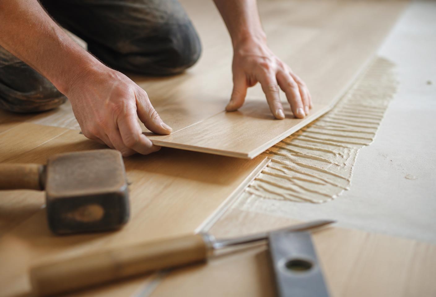 Craftsman laying a wooden floor plank
